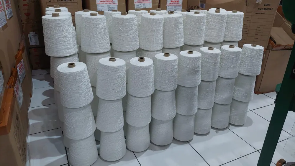 Barisan cone benang putih tertata rapi di gudang