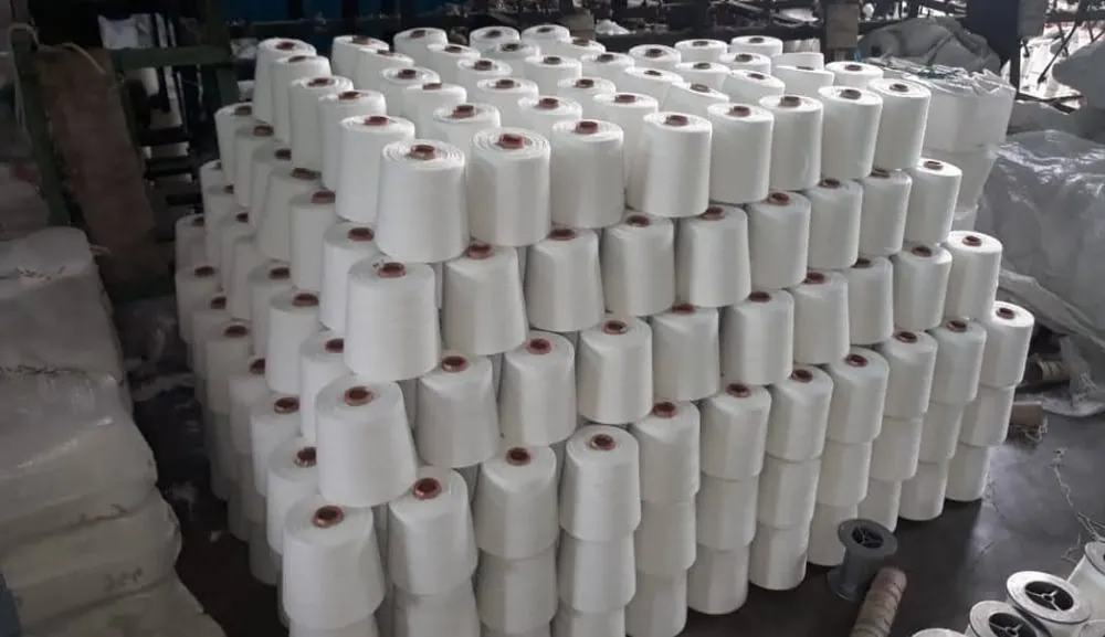 Tumpukan cone benang putih di area gudang produksi