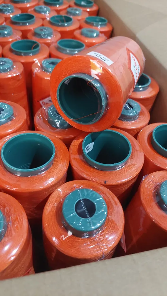 Cone benang warna oranye berinti hijau di dalam dus