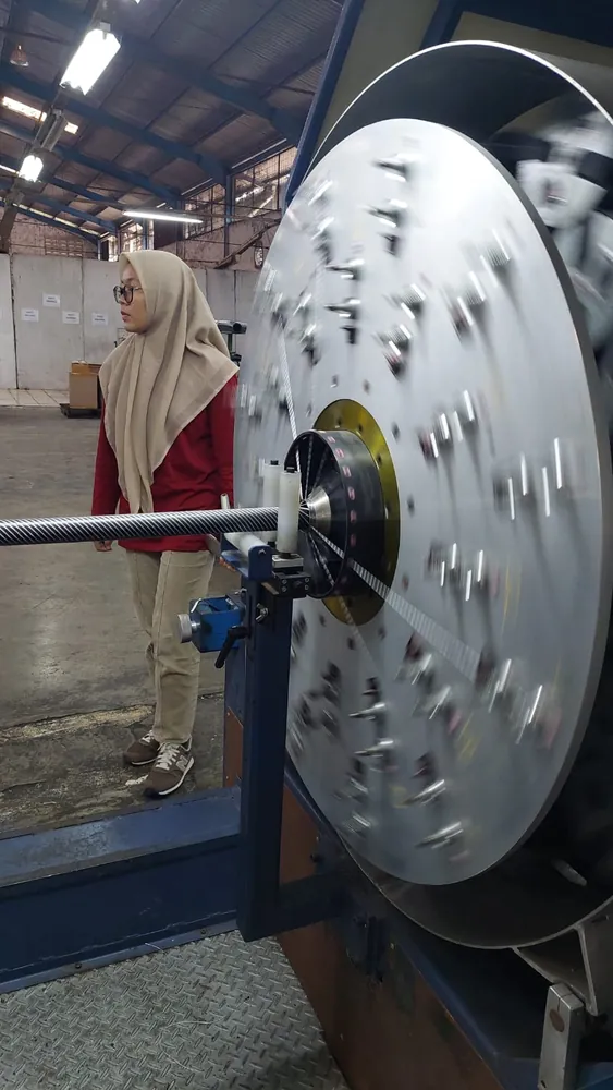 Operator mengawasi mesin twisting benang yang sedang berputar