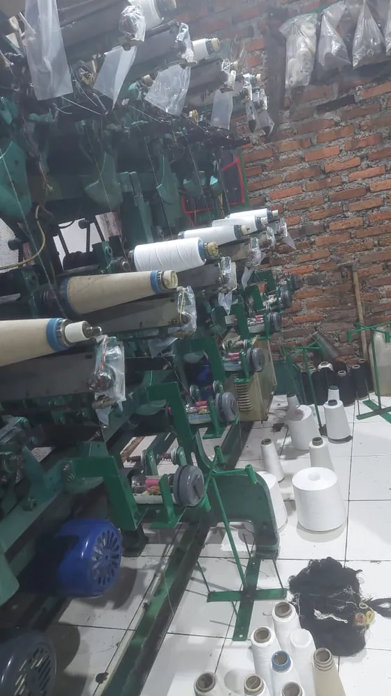 Mesin twisting dengan bobin benang putih terpasang