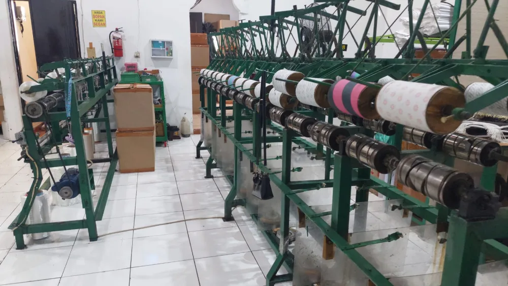 Mesin twisting dengan roll benang aneka warna siap digulung