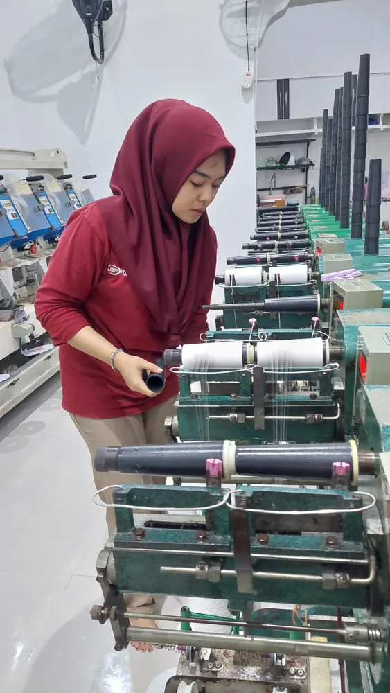 Operator memasang bobin pada mesin twisting benang
