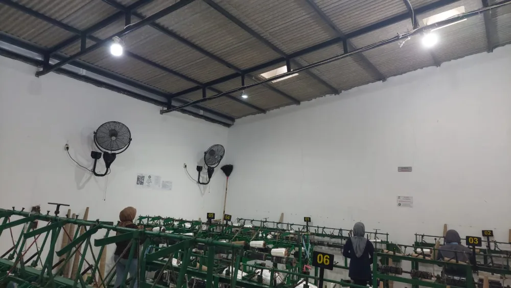 Ruang produksi dengan stasiun mesin bernomor dan kipas pendingin dinding